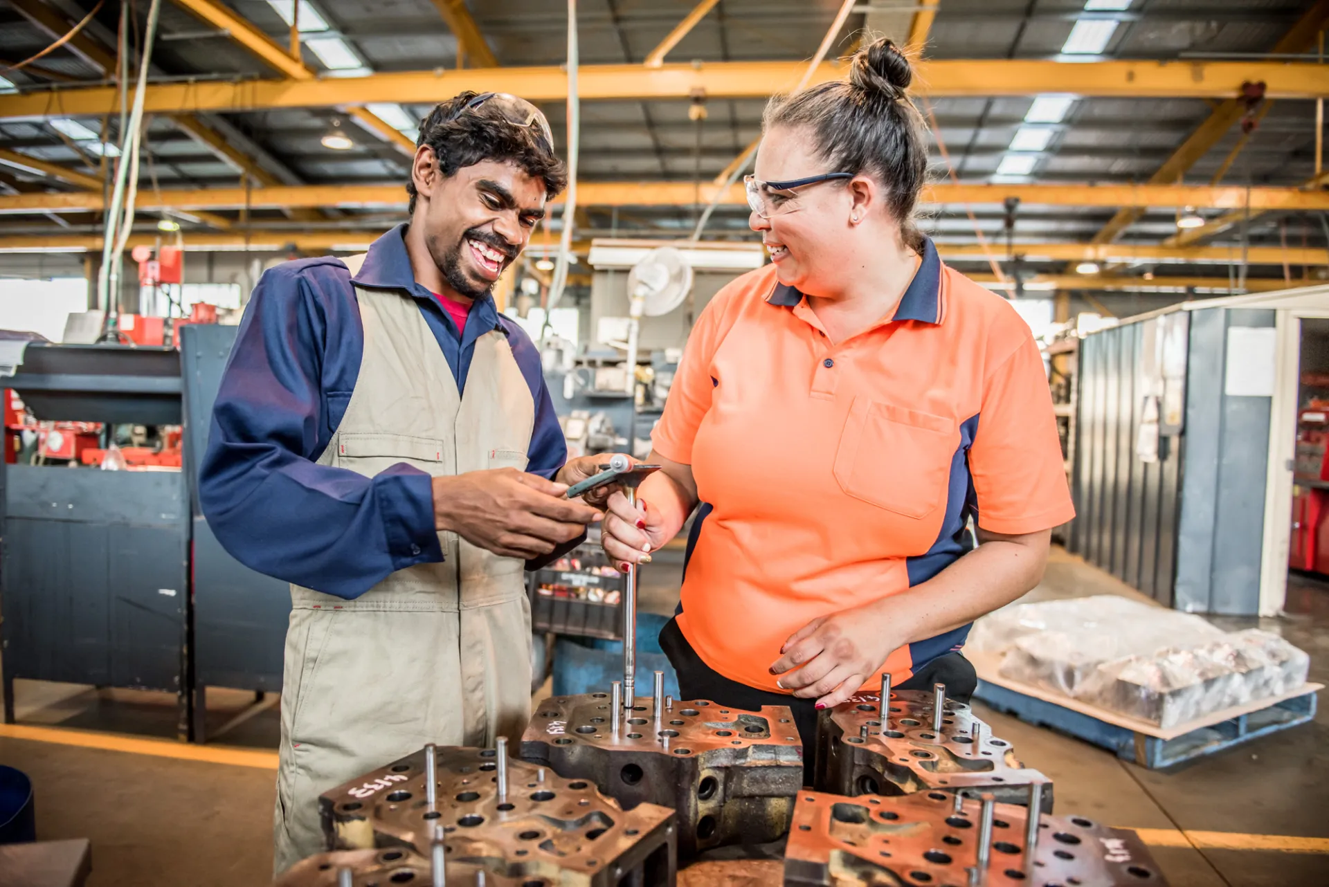Diversity and Inclusion First Nations young man metal work factory indoors high-vis woman mentor mentoring clothing engineering indoor job man person technician workshop